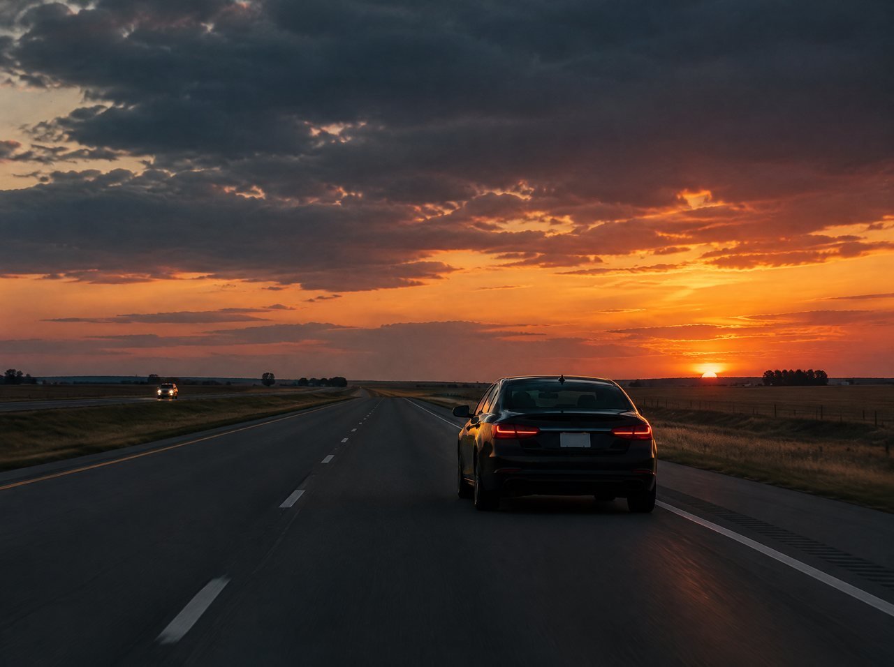 A black car on an open highway at dusk